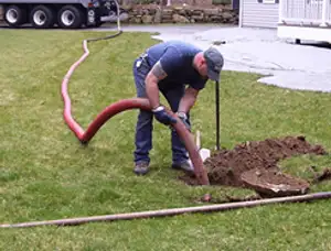 Septic pumping technician servicing a residential septic tank with a vacuum hose in Berkeley, CA
