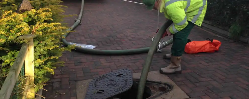 Septic tank cleaning technician servicing a septic tank with a vacuum hose in Berkeley, CA