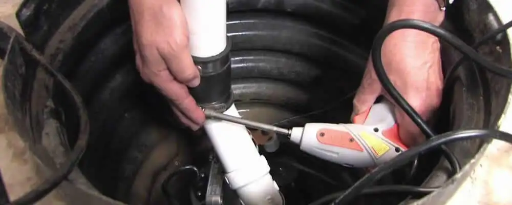 Sump pump installation technician connecting PVC discharge piping in Berkeley, CA