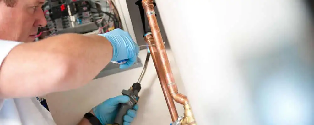 Water heater repair technician testing copper pipe connections and controls in Berkeley, CA